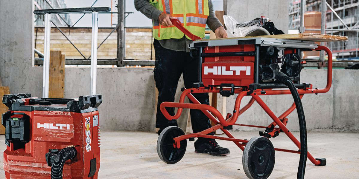Cropped application image of vacuum cleaner and table saw SCT 60-22 (G01) with wood board and push stick.